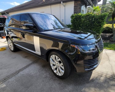 A black Ranger rover SUV ina tampa bay drive way surrounded by mobile detailing equipment