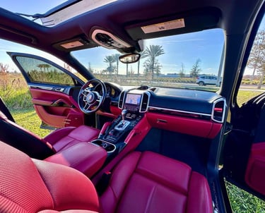 Interior of a luxury SUV with red leather seats and black trim, freshly detailed and parked under clear Florida skies