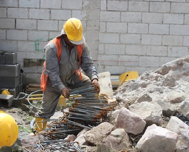 a man in a yellow helmet working with construction materials