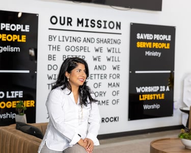 Melissa, founder of Bee the Light Designs sitting in from of her designed church mission wall
