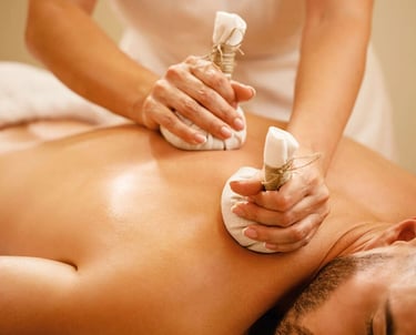 A man getting thai herbal compresses pressed into his back during a massage.