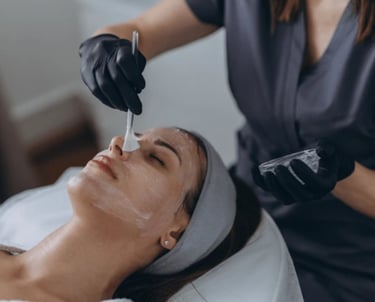 Woman getting a chemical mask brushed onto her face.