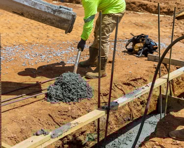 a man in a yellow jacket is pouring concrete into a concrete slab