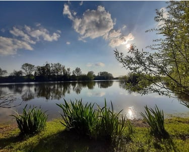 a lake with a sun shining through the clouds