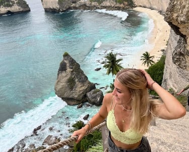 A blonde woman overlooks the turquoise waters and limestone cliffs of Diamond Beach in Nusa Penida, Bali.