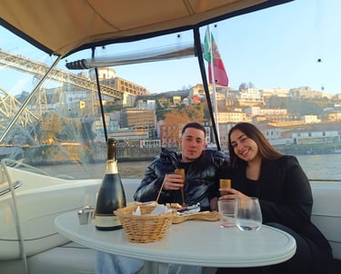 A couple enjoying a private boat tour in Porto with champagne and views of the Dom Luís I Bridge.