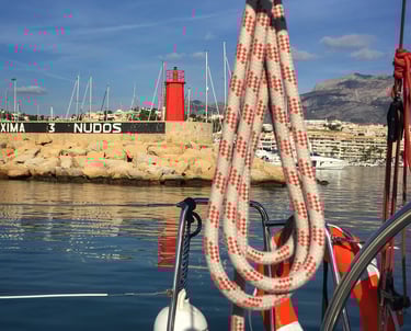 Port entrance with view of lighthouse and ropes on flat calm sea
