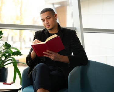 a man sitting on a couch reading a book