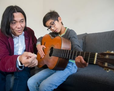 Guitar instructor demonstrating a playing technique to a student