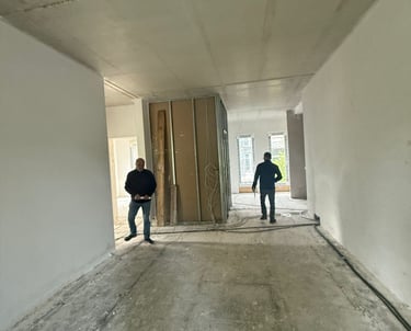 Zwei Bauarbeiter in einem unfertigen Raum mit offener Tür – Baustellenszene im Innenausbau