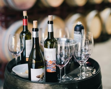 wine bottles and wine glasses on a barrel of wine