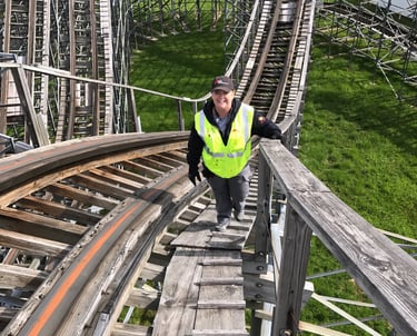 a woman in a safety vest is walking up a wooden roller coaster