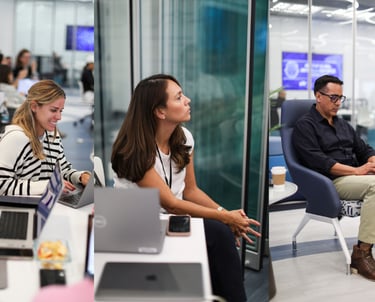 a group of people sitting at a table with laptops using AI to code