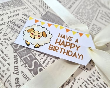 Birthday tag with cute sheep on it, on a present wrapped in newspapers.
