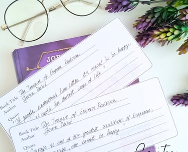 Two printed bookmarks with written quotes on them. Glasses near by.