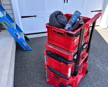 Red rolling modular tool box system stacked on a driveway next to a blue ladder.