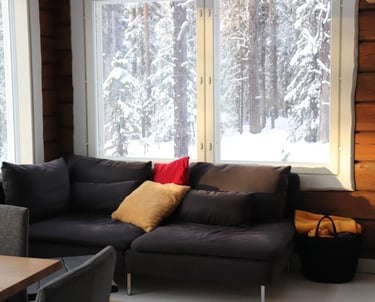 comfortable couch in a log cabin living room, big panoramic windows with views of snowy forrests