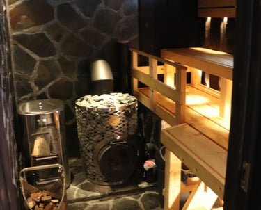 rustic sauna with iki kiuas and slate rockwork, burnt panels and dim lighting