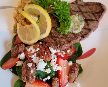 Beautifully garnished steak with compound butter and spinach, strawberry, pecan, goats cheese saladl
