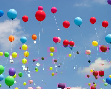 Ballons multicolores s’envolant dans le ciel, porteurs de messages d’amour et d’adieu.