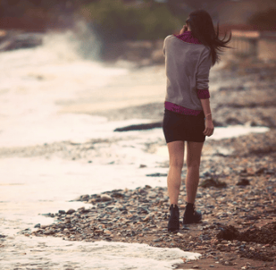 Femme marchant en bord de mer dans un moment de réflexion intérieure