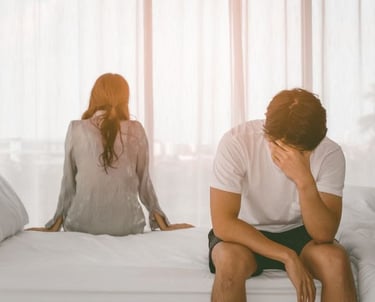 a man and woman sitting on a bed