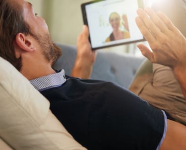 a man is sitting on a couch and holding a tablet