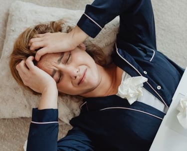 a woman in pajamas crying and is laying on a pillow