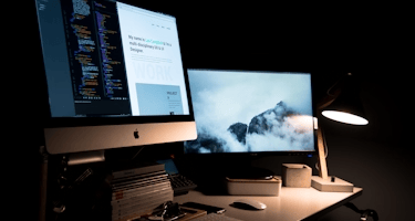 escritorio con 1 computadora con 2 monitores mostrando diseño de una web