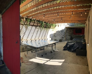 Outdoor garage man cave with bar, TV, and roof overhang performed by Golden Rule Construction