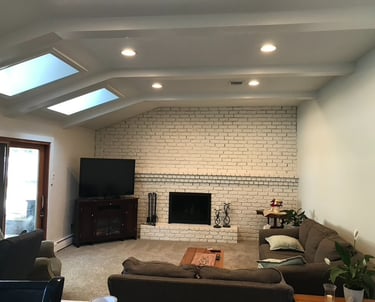 White painted brick fireplace updated living room renovation with skylights and recessed lighting