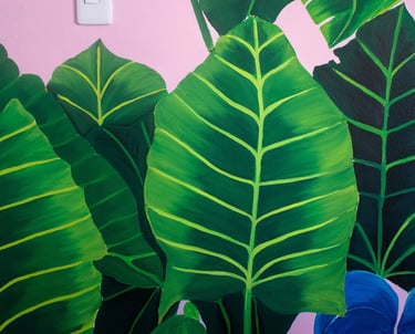 Hojas tropicales pintadas con realismo sobre mural decorativo y ambientación.