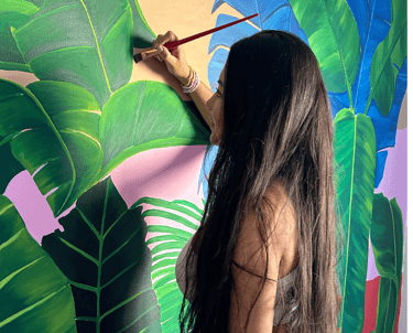Pintora trabajando en mural artístico interior, arte contemporáneo personalizado con acrílico.