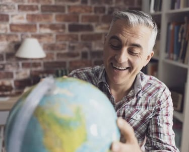 Homem sorridente segurando globo terrestre, representando expatriados e mobilidade global.