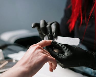 A manicurist in black gloves is doing a customer's nails.