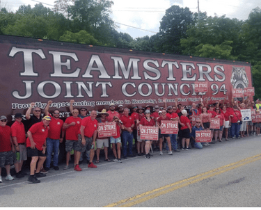 Large group in front of Teamsters truck with strike signs
