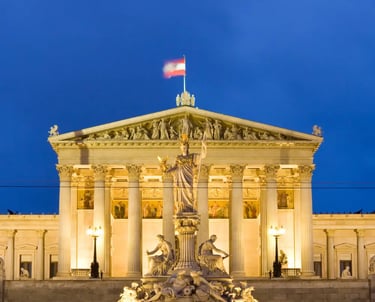 Vienna Parliament building lit up at night with Austrian flag and Athena fountain