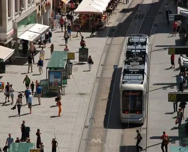 A tram passing through a busy pedestrian street in the historic center of Graz.