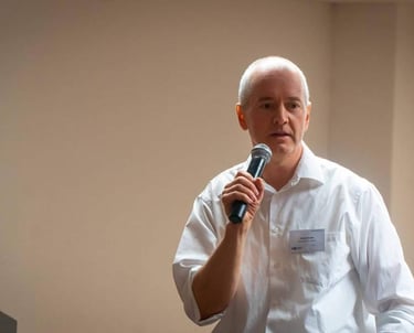 Jörg Grube hält beim Vortragen ein Mikorophon in der Hand