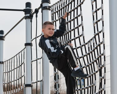 Garçon grimpant sur une structure Kenguru Pro Kids Active Play en extérieur.