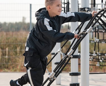 Garçon grimpant sur une structure Kenguru Pro Kids Active Play en extérieur.