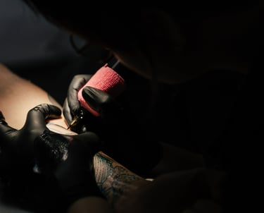 Photo d'une séance de tatouage ou l'on voit les mains de la tatoueuse tenant le dermographe 