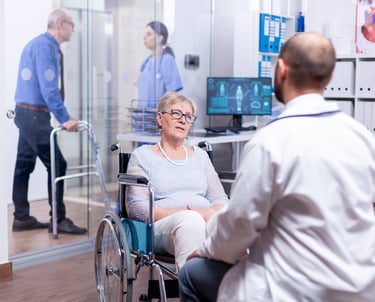 mulher em cadeira de rodas conversando com medico em sala com mais pessoas