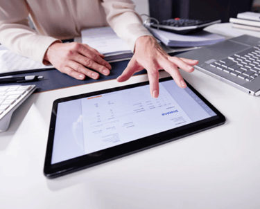 mãos digitando em tablet trabalhand com outros equipamentos proximos