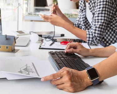 duas pessoas trabalhando bastante e observando computador, plantas tecnicas e digitando