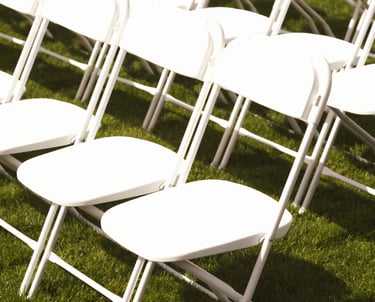 Sillas blancas plegables para eventos al aire libre en el paso
