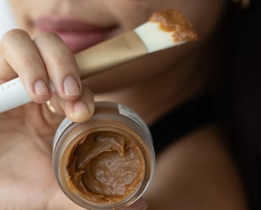 woman holding up a brown mask and a brush