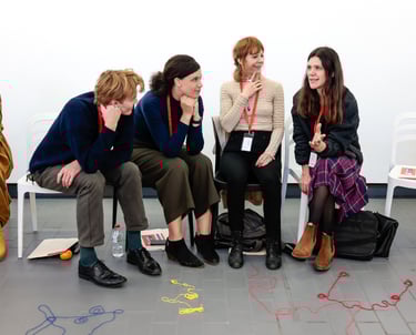 Four adults listening and thinking with smiles on their faces.
