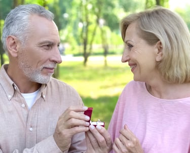 a man and woman are smiling and holding a ring
