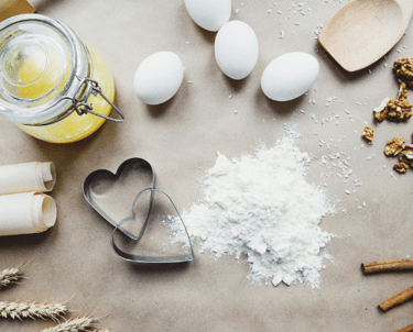 A cooking work table spread with eggs, rice, sticks of cinnamon, and two heart-shaped cookie cutters